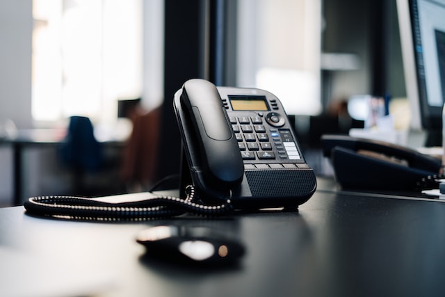 Black landline phone sitting on a desk in an office
